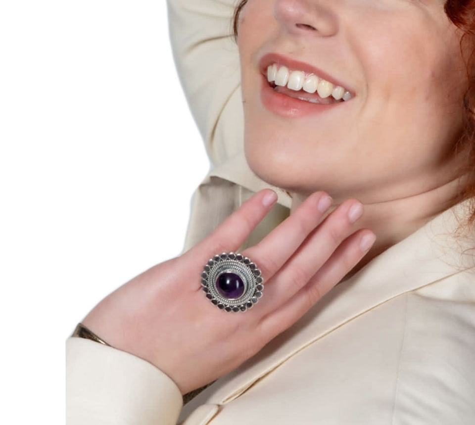 Woman wearing a chunky Taxco silver ring with amethyst cabochon on a white background