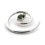 Close-up angled view of a hand-detailed silver spiral pendant highlighting the faceted green tourmaline setting.