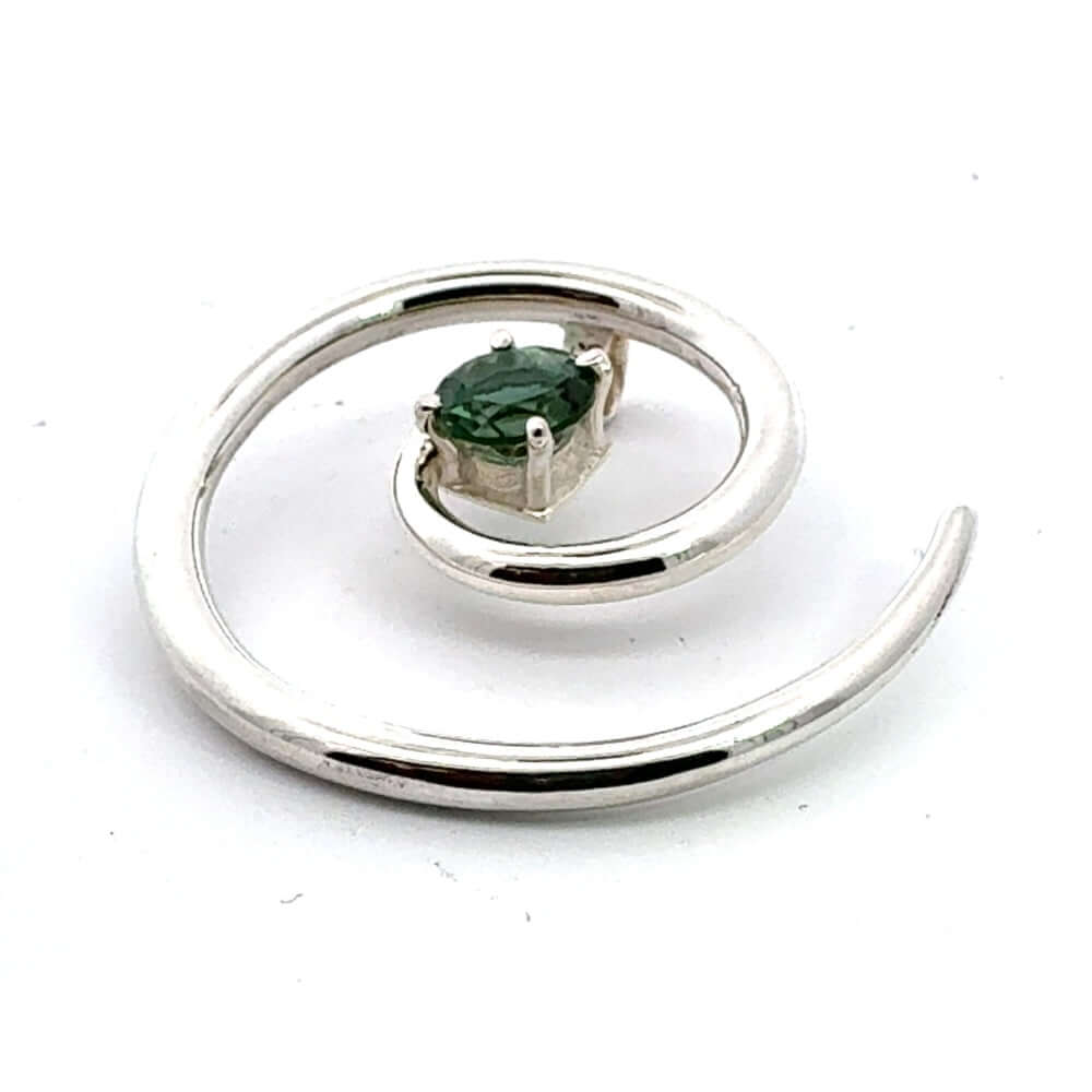 Close-up angled view of a hand-detailed silver spiral pendant highlighting the faceted green tourmaline setting.