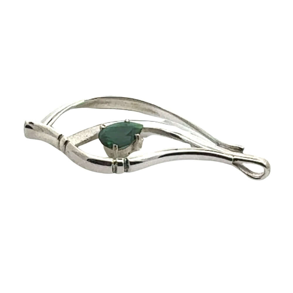 Side profile of a handcrafted silver pendant showing the depth of the metalwork and the secure prong setting of the green peridot.