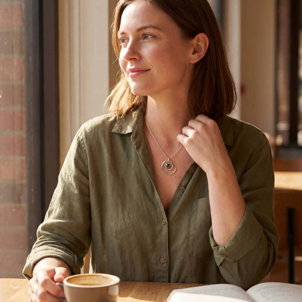 Lifestyle shot of a woman wearing the green tourmaline silver spiral pendant on a delicate chain.