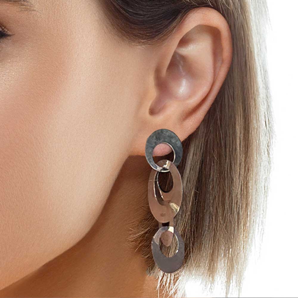 Close-up of an ear wearing a unique earring with circular components.