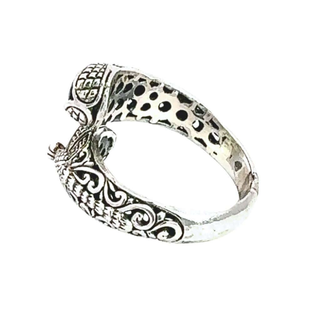 Silver ring with intricate designs on a white background