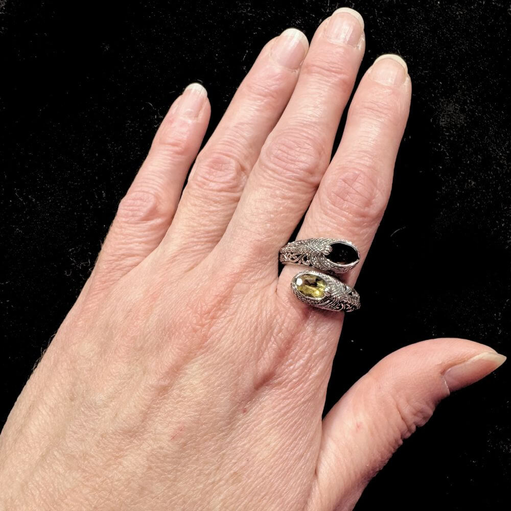 Hand wearing asilver ring with gemstones on a black background