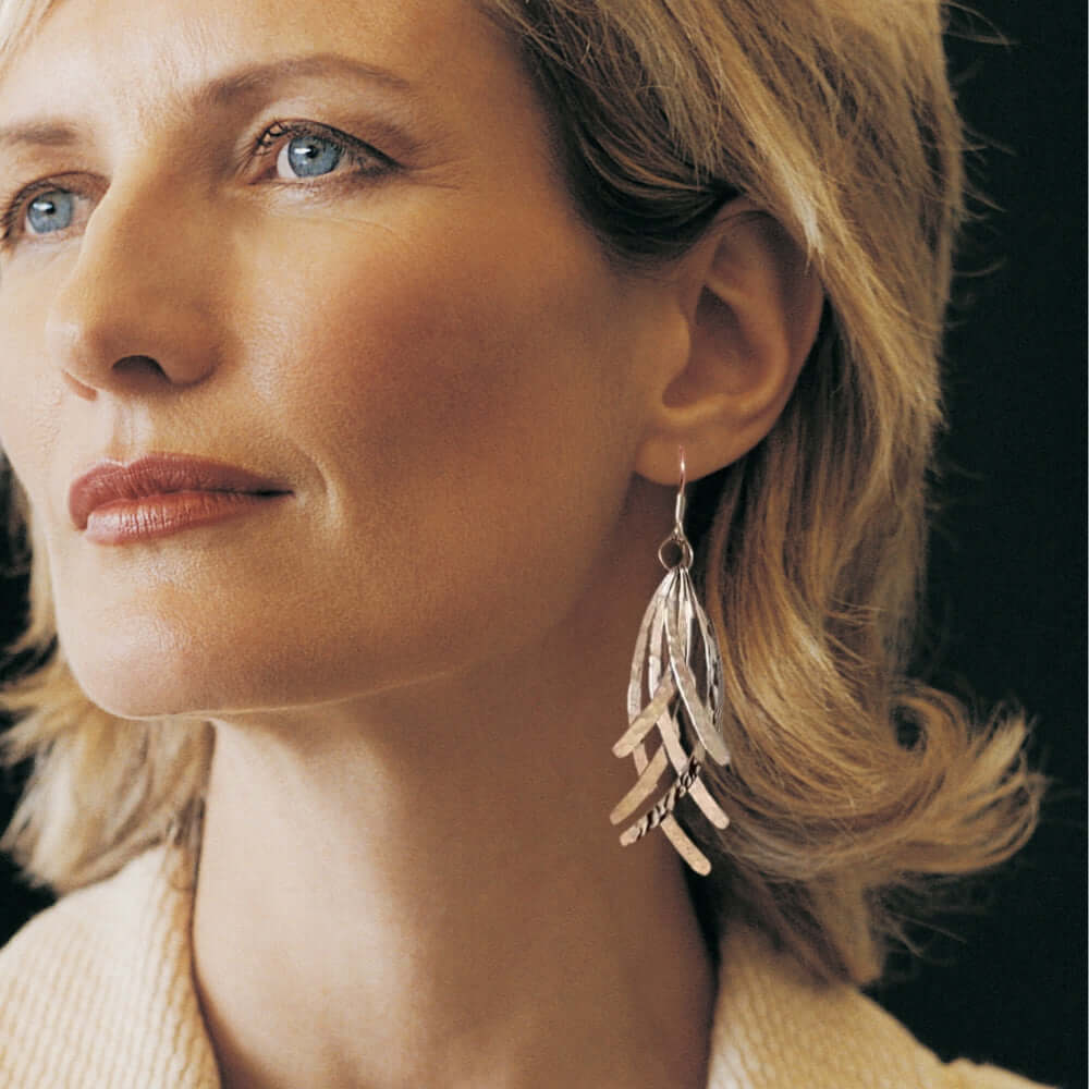 Close-up of a woman wearing feather silver earrings with a blurred background