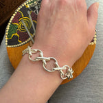 Hand wearing a silver chain bracelet with a colorful background