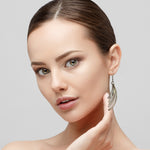 Woman wearing a silver earring against a neutral background