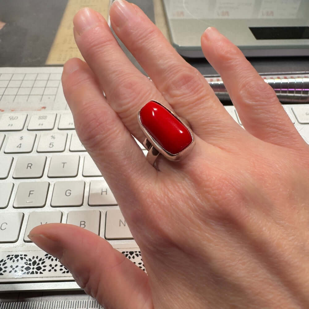 Hand with red coral and silver ring on a keyboard