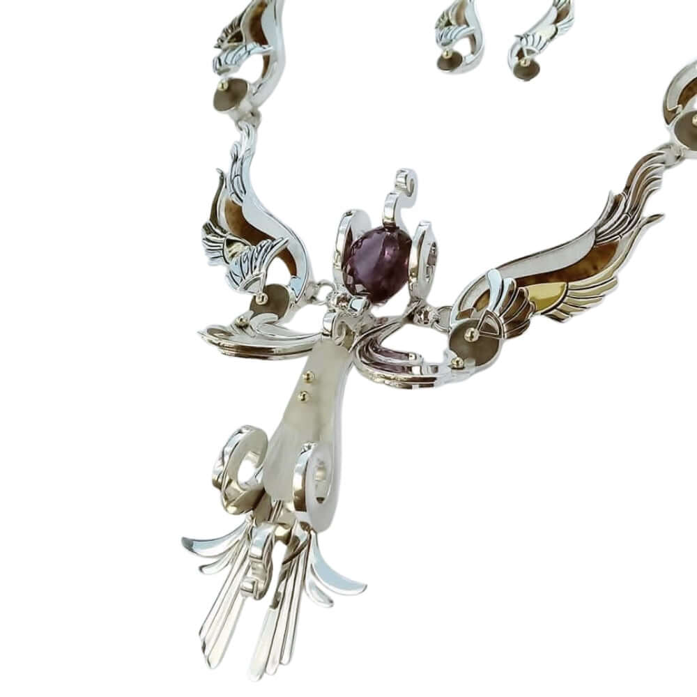 Ornate silver necklace with a central gemstone on a white background