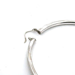 Closure system of 8 cm silver hoop earrings on a white background