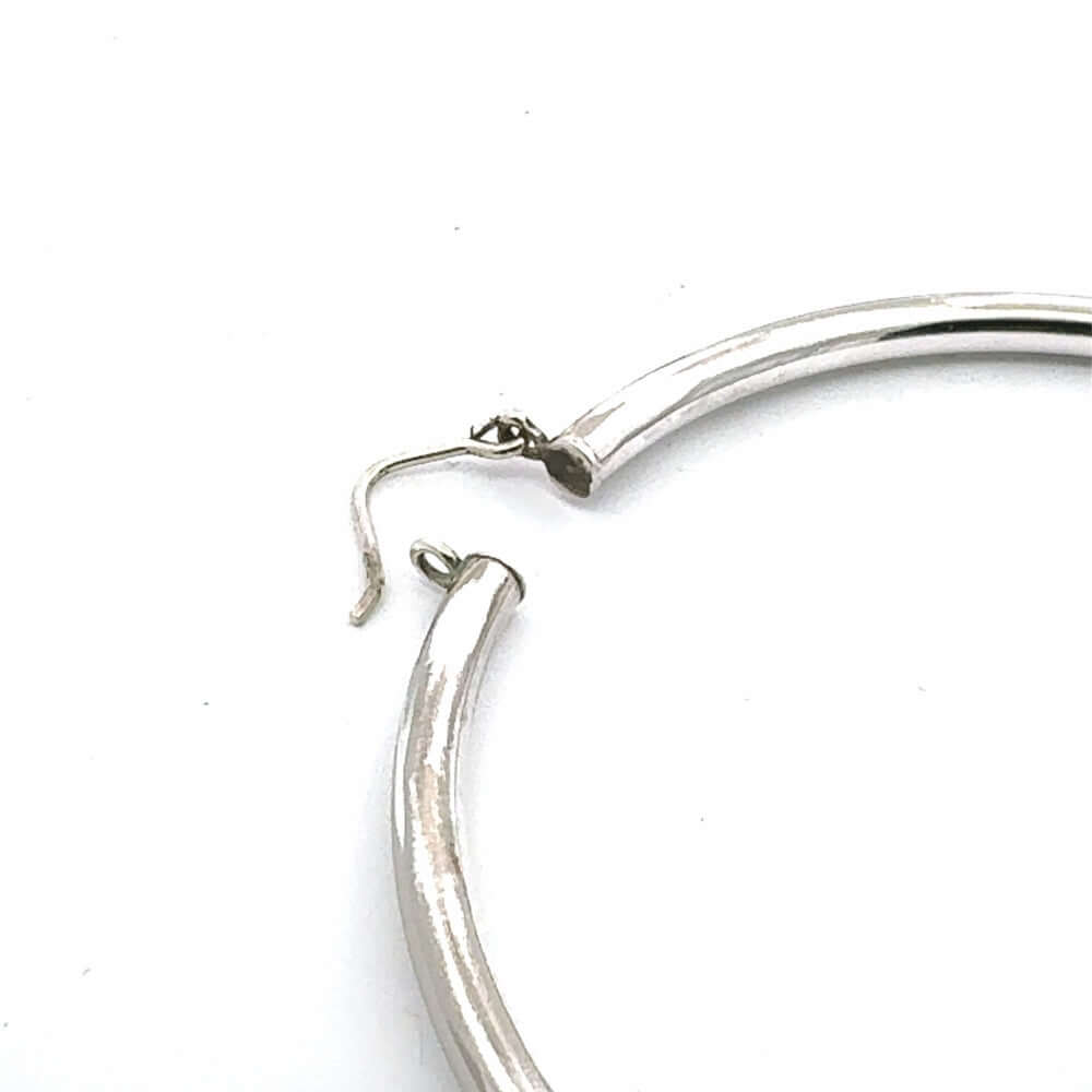 Closure system of 8 cm silver hoop earrings on a white background