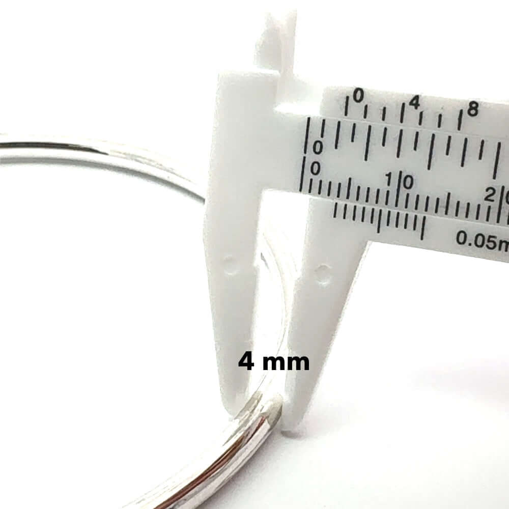 Close-up of a silver hoop earring with a caliper measuring its thickness on a white background.