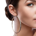 A side profile of a woman wearing a sleek and elegant sterling silver hoop earring.
