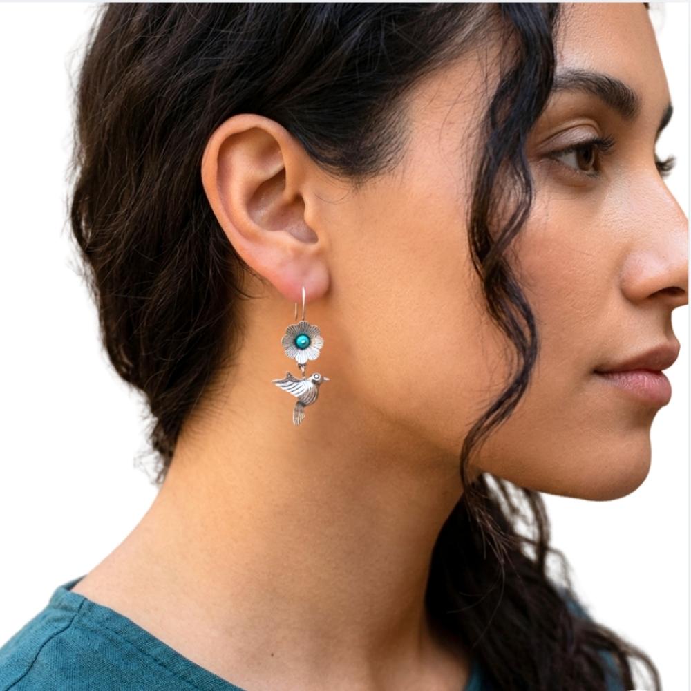 Close-up of a woman wearing a floral silver earring  and a bird with a white background