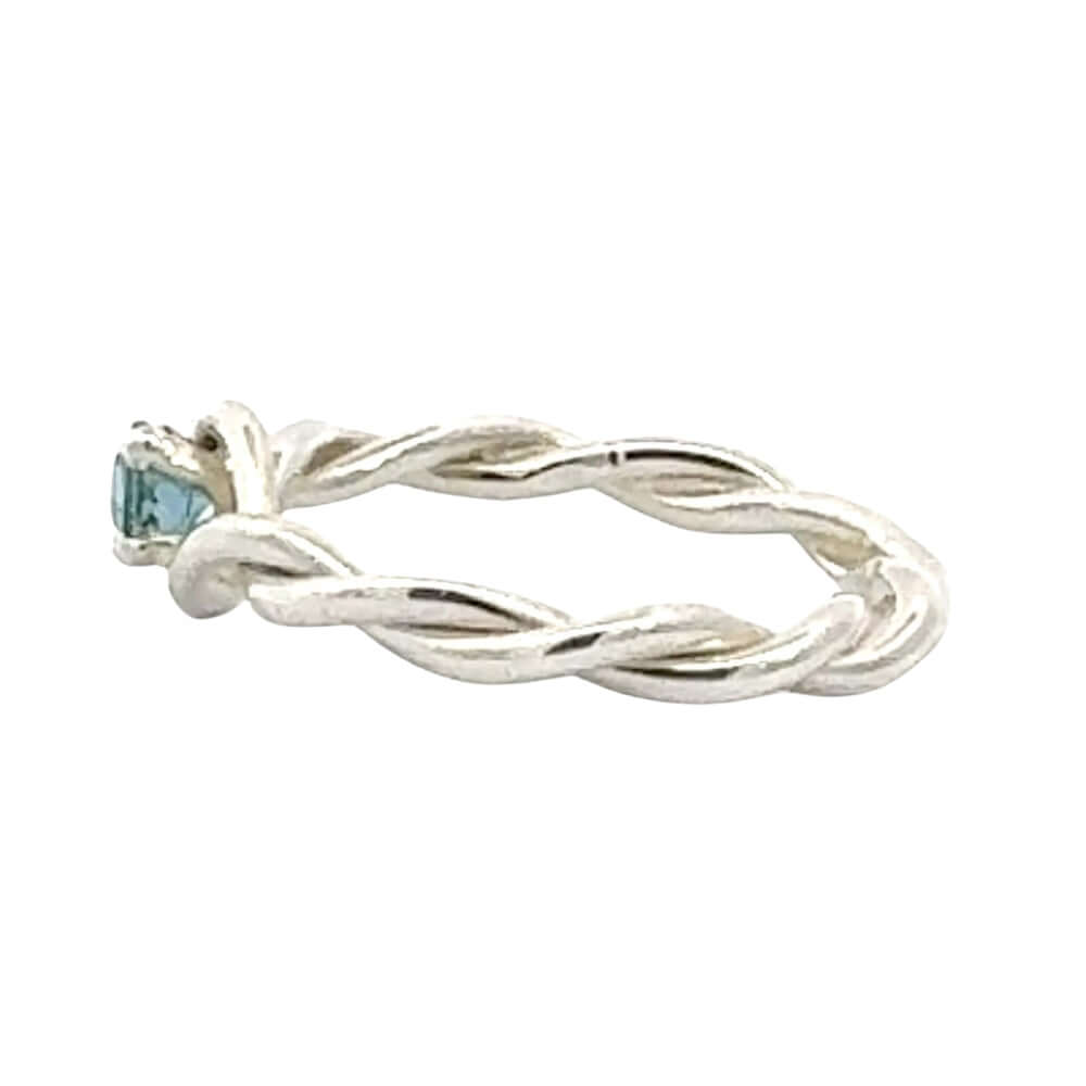 Silver twisted ring with a blue gemstone on a white background