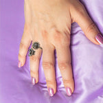 Hand with a decorative ring on a purple fabric background