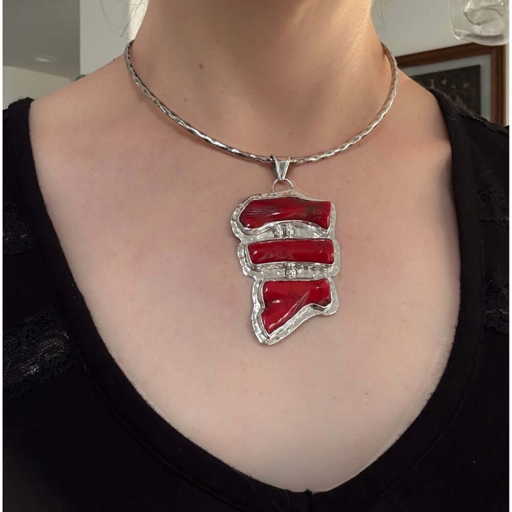 Necklace with a red coral and silver pendant worn by a person