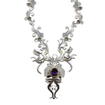 Ornate necklace with a central amethyst gemstone on a white background