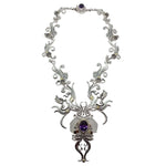 Ornate silver necklace with purple gemstones on a white background