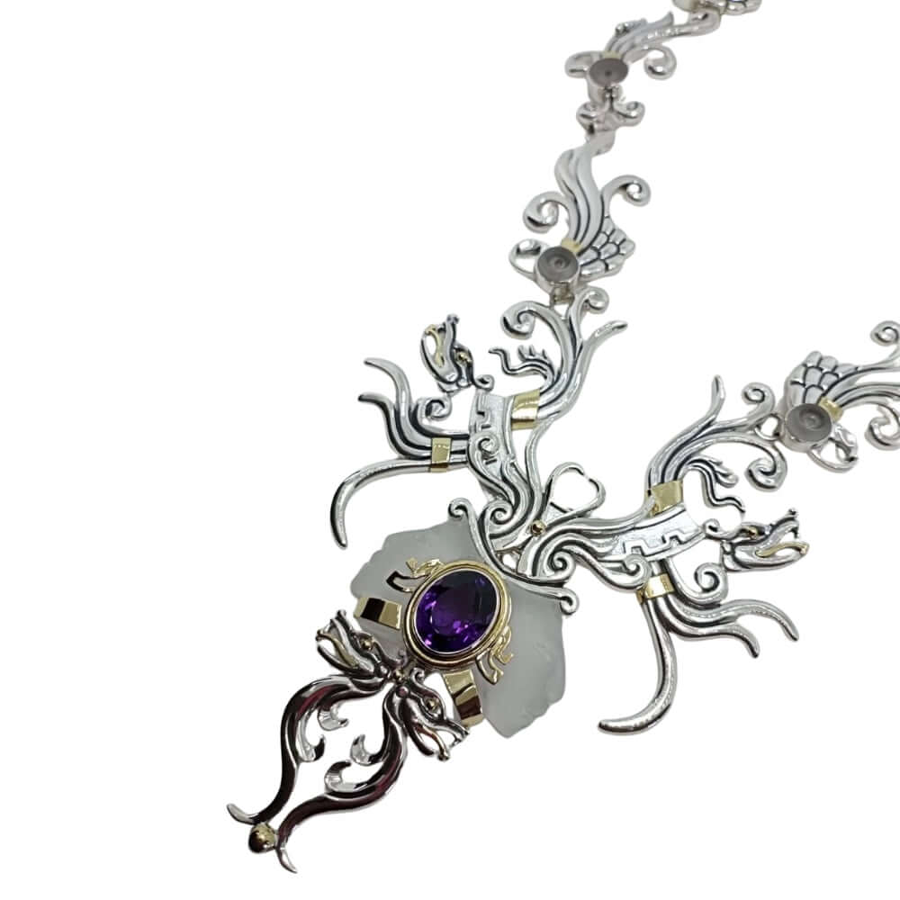 Ornate silver necklace with a purple gemstone on a white background side view