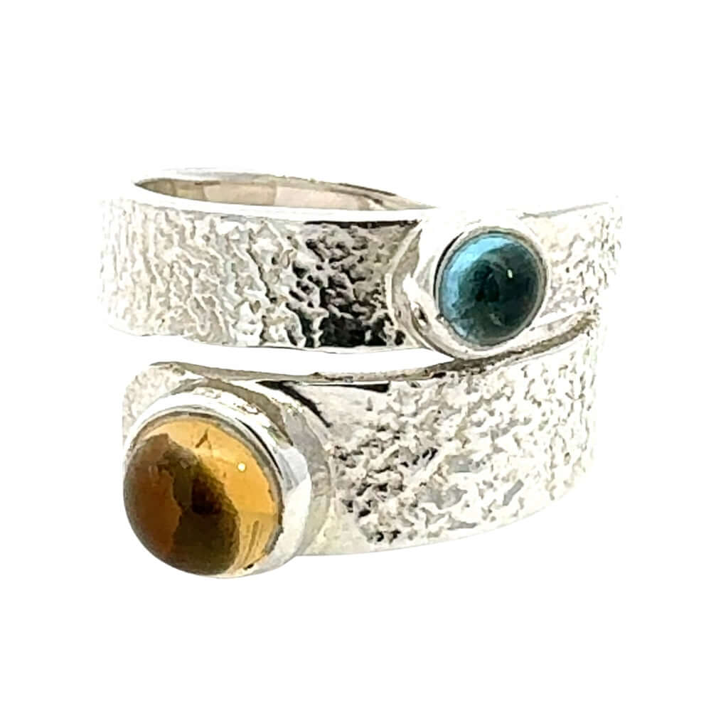 Silver ring with yellow and blue gemstones on a white background