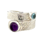 Silver ring with amethyst and blue topaz on a white background
