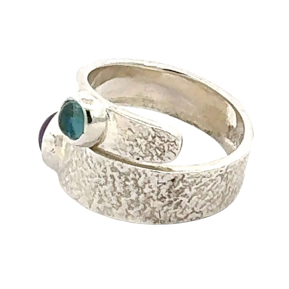 Silver ring with a textured band and gemstone on a white background
