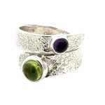 Silver ring with green and purple gemstones on a white background
