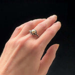 Hand wearing a silver ring with a pearl on a black background