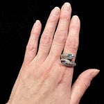 Silver ring with gemstones in hand over black background