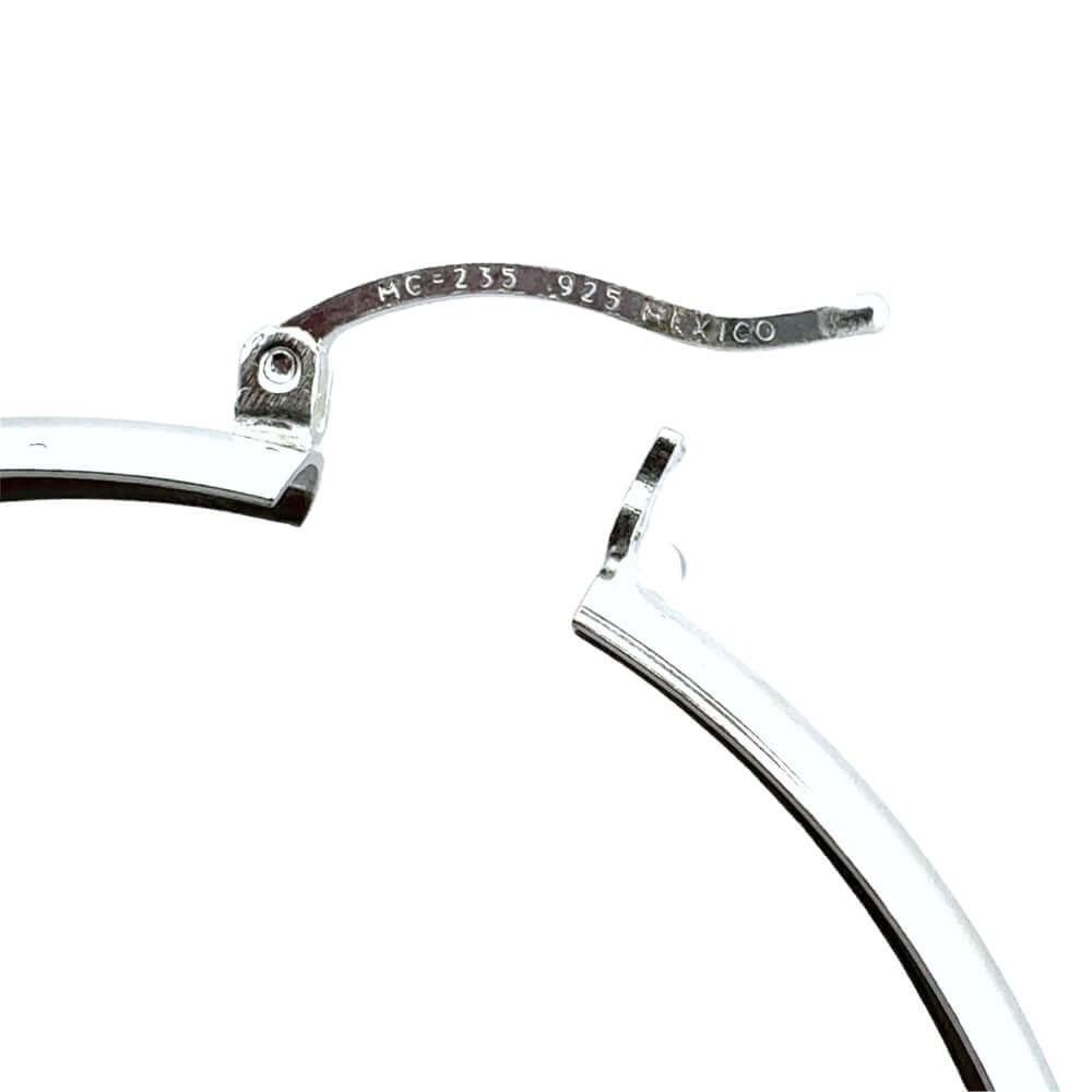 Close-up of a silver earring with 'Mexico' inscription on a white background