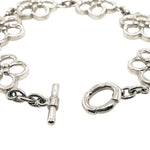 A silver-tone chain bracelet with repeating openwork floral links and a toggle clasp, photographed on a plain white background.