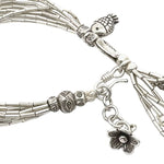 Silver beaded bracelet with tassels and floral charm on a white background
