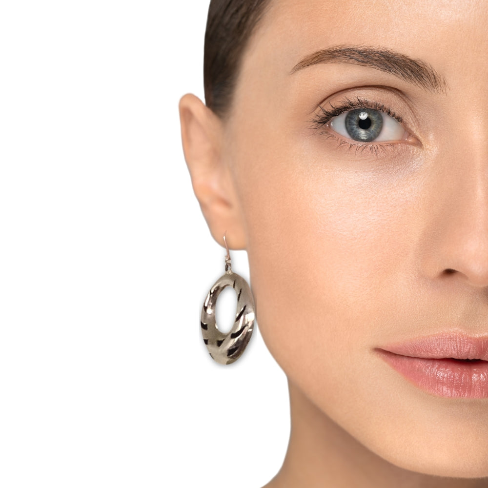 Close-up of a woman wearing silver hoop earrings on a white background
