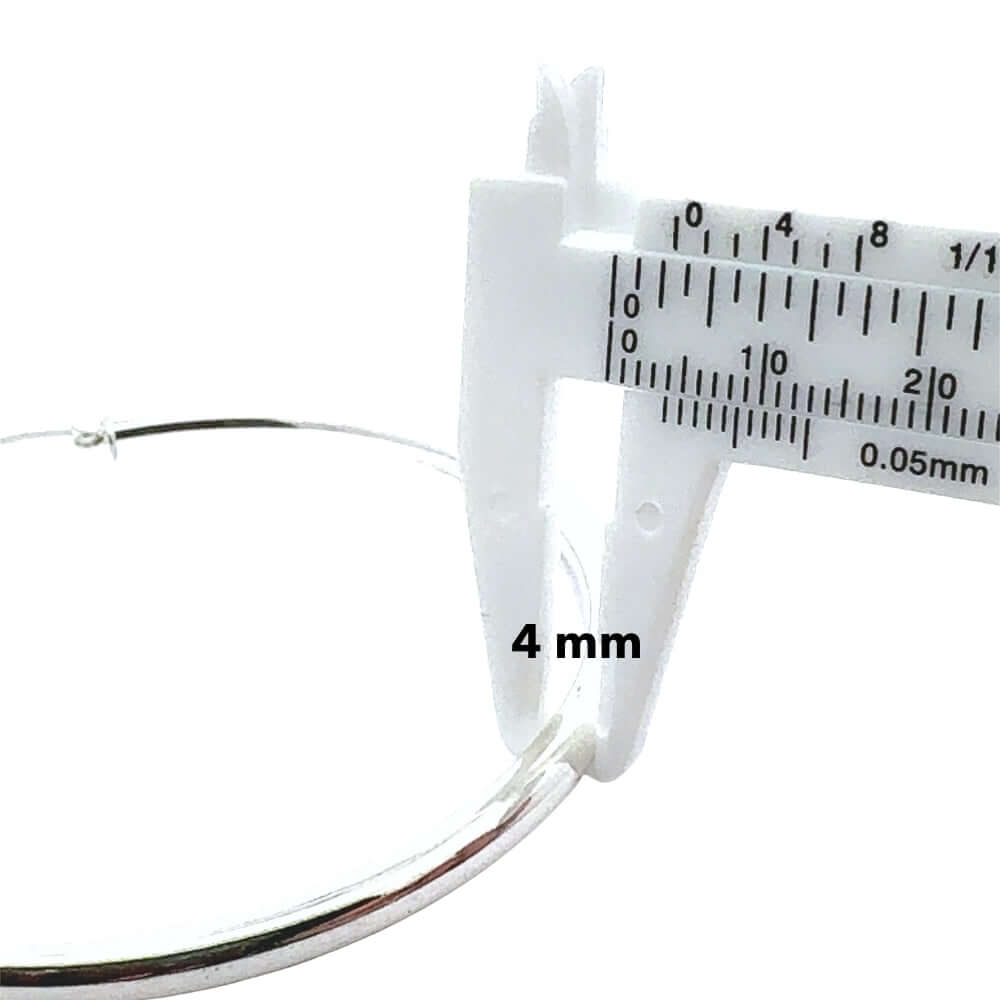 Close-up of a silver hoop with a micrometer measuring its diameter on a white background