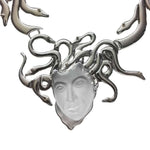 Silver necklace with a face design and snake-like branches on a white background