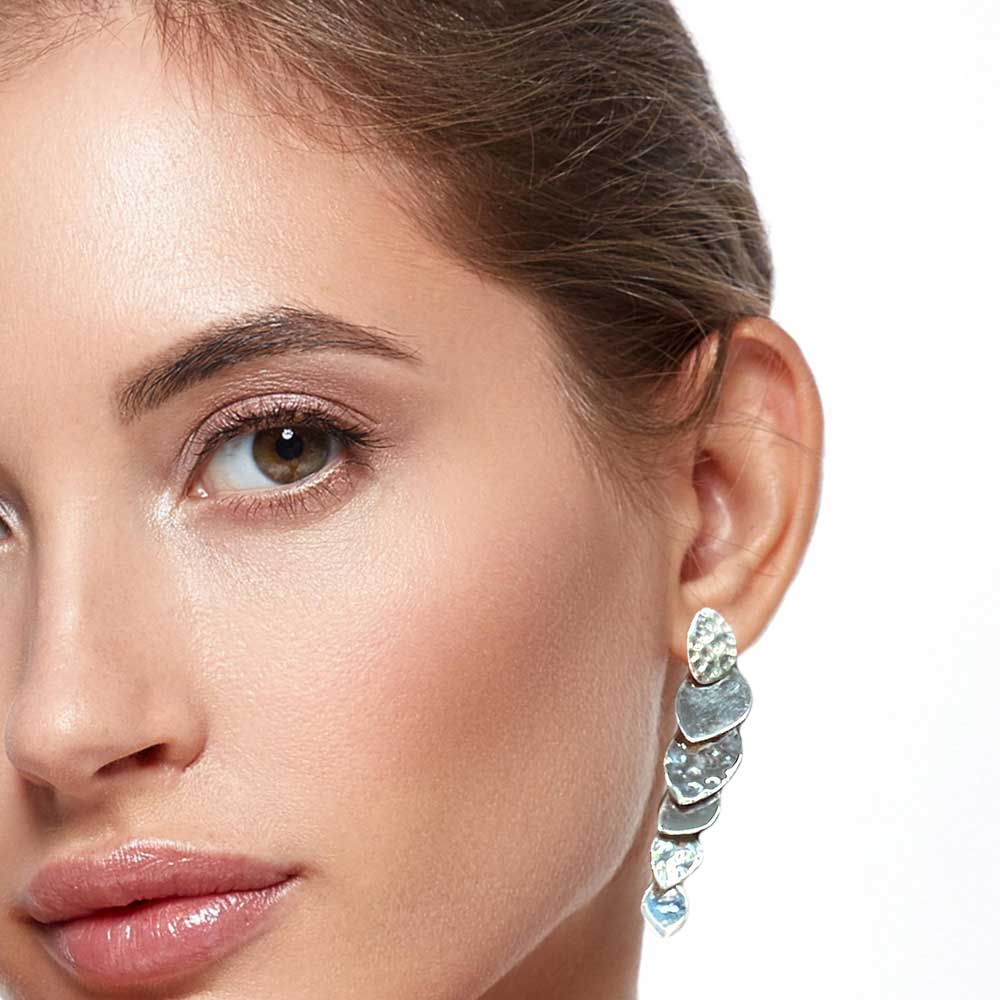 Close-up of a woman wearing a sparkling silver earring on a white background