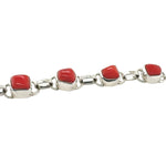 Silver bracelet with red coral on a white background