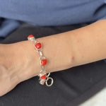Bracelet with red coral and silver on a wrist against a blue shirt background