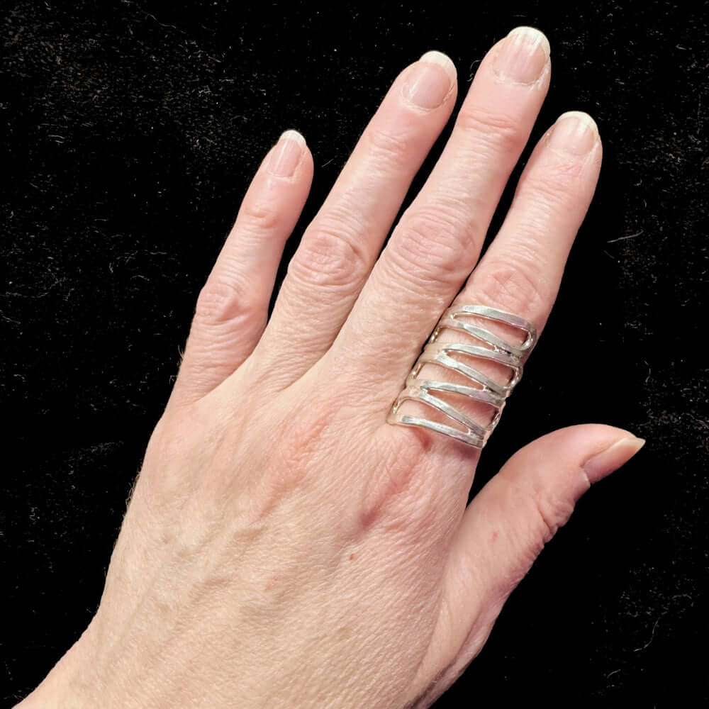 Hand wearing a silver ring on a black background