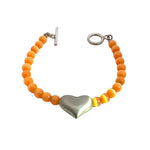 Bracelet with orange cats eye beads and a silver heart charm on a white background