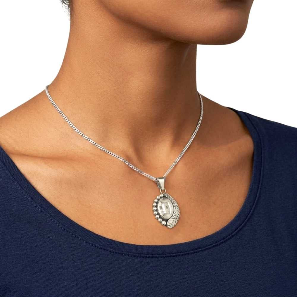 Silver necklace with a pendant on a person wearing a navy blue top.