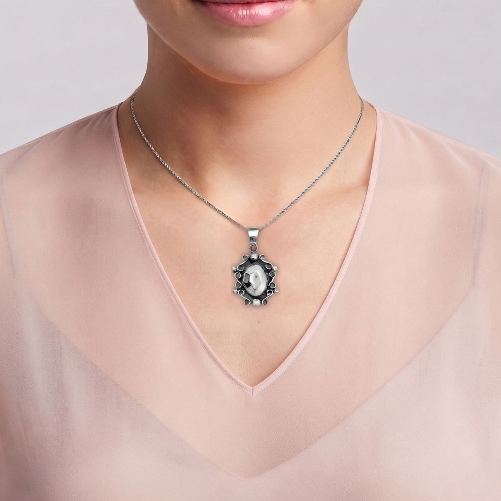A close-up of a model wearing a silver  oval pendant 