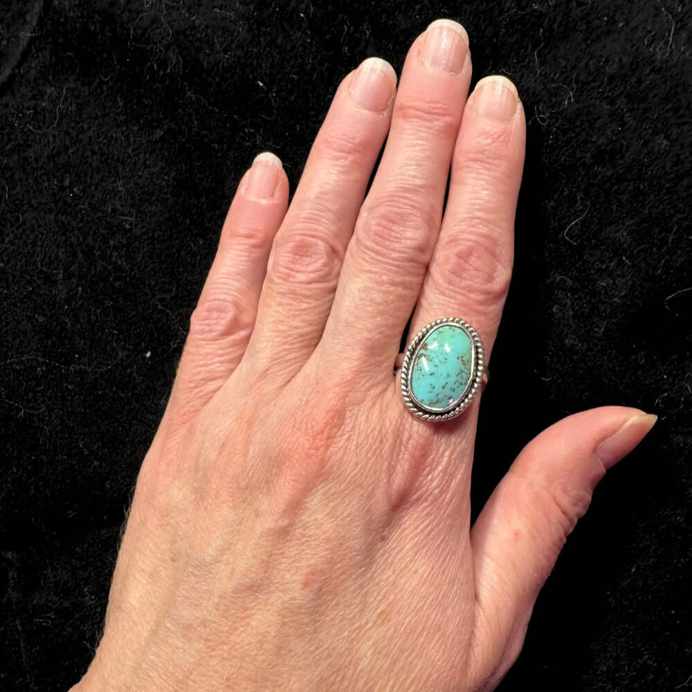 Hand wearing a turquoise ring on a black background
