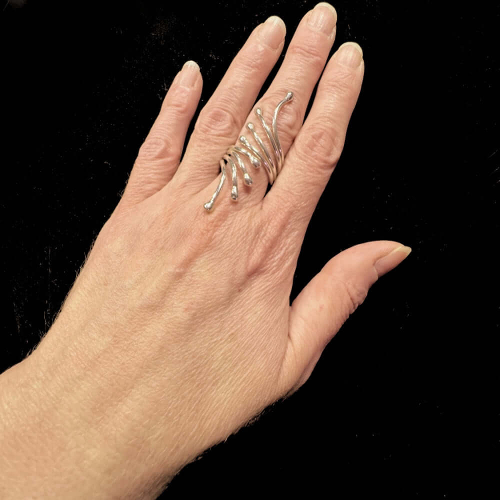 Hand wearing a silver ring with a black background