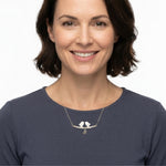 Woman wearing a handmade silver birds necklace with a white background