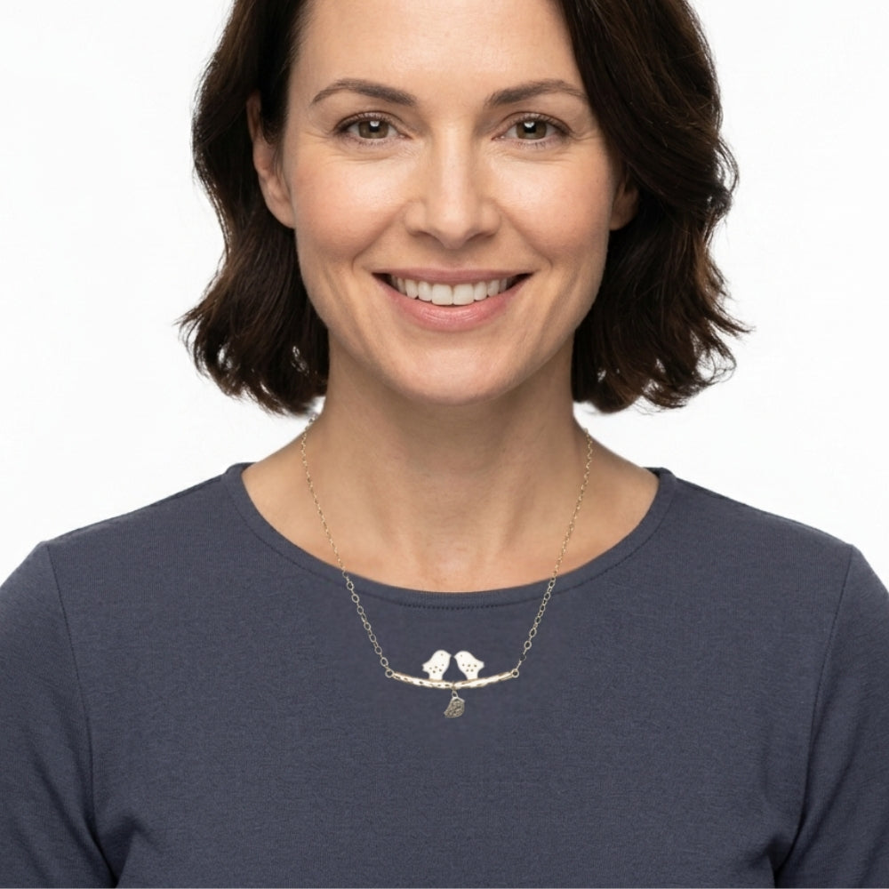 Woman wearing a handmade silver birds necklace with a white background
