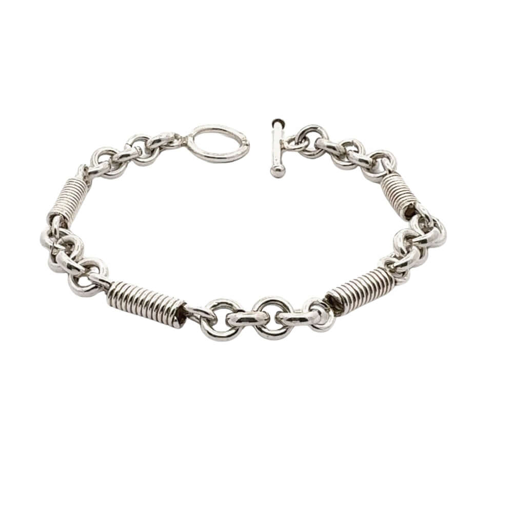 Silver bracelet with coil design and rings in white background