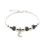 Silver bracelet with black and white beads and a heart charm on a white background