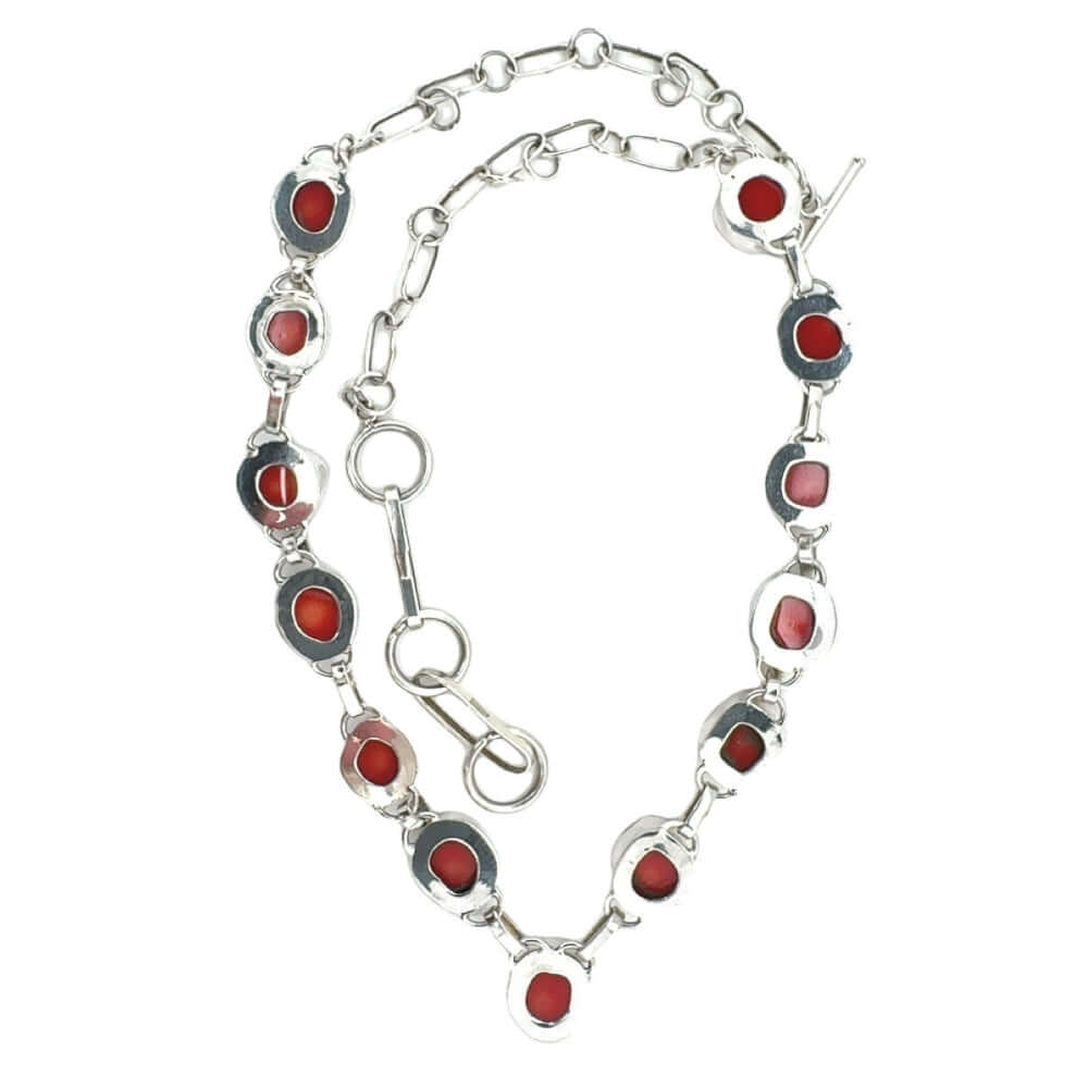 Silver necklace with red coral from the back on a white background